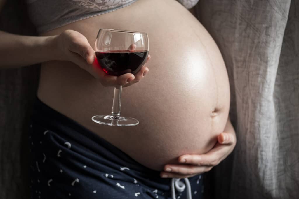 Schwangere mit Weinglas in der Hand