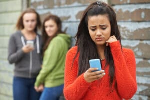 Mädchen guckt bedrückt auf ihr Handy