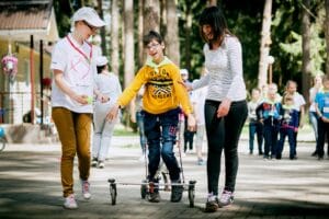 Junge im Rollator mit 2 Betreuerinnen