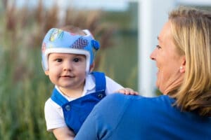 Kind mit Kopfhelm auf Mamas Arm