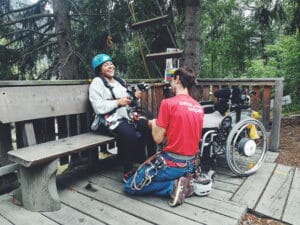 Rollifahrerin wird für Hochseilgarten vorbereitet