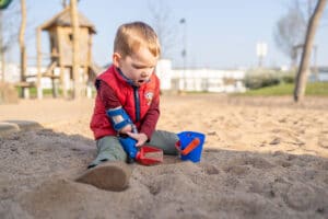 Junge mit Armprothese spielt im Sand