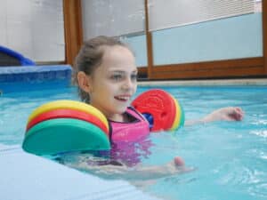 Emma, ein Mädchen mit Handicap und mit Schwimmhilfe im Wasser