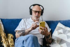 Mann mit Kopfhörern und Smartphone auf Sofa