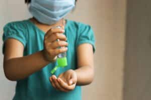 Krankenschwester mit OP-Maske und Desinfektionsmittel