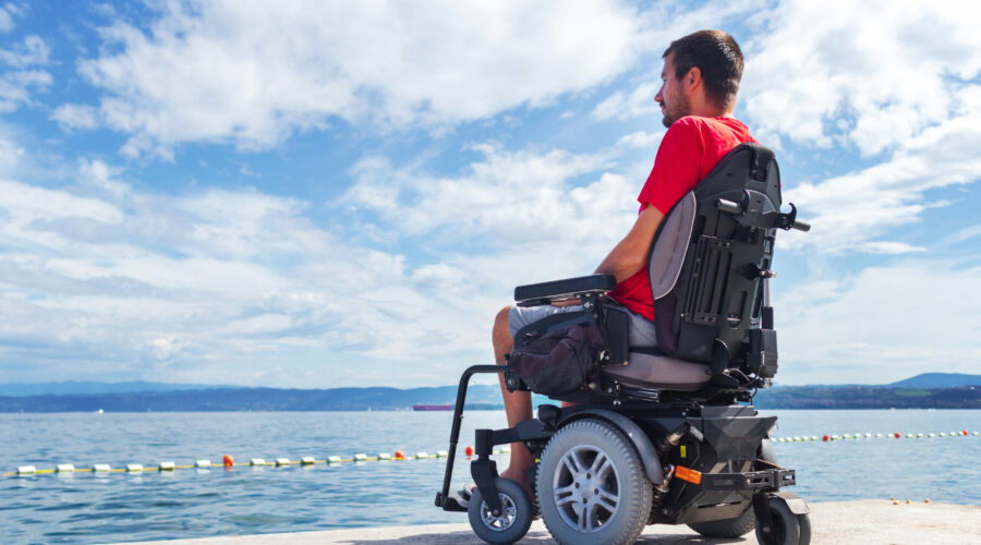 Man,With,Muscular,Dystrophy,On,Electric,Wheelchair,Outdoors,Looking,At