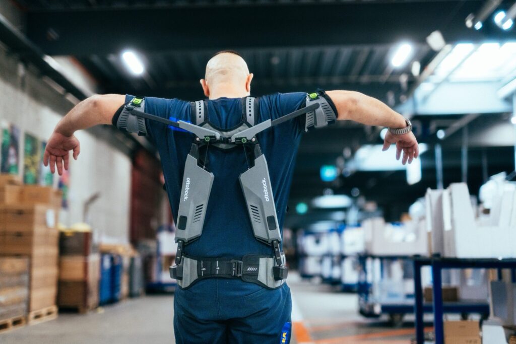Person tr&auml;gt ein Exoskelett in einer Logistikumgebung.