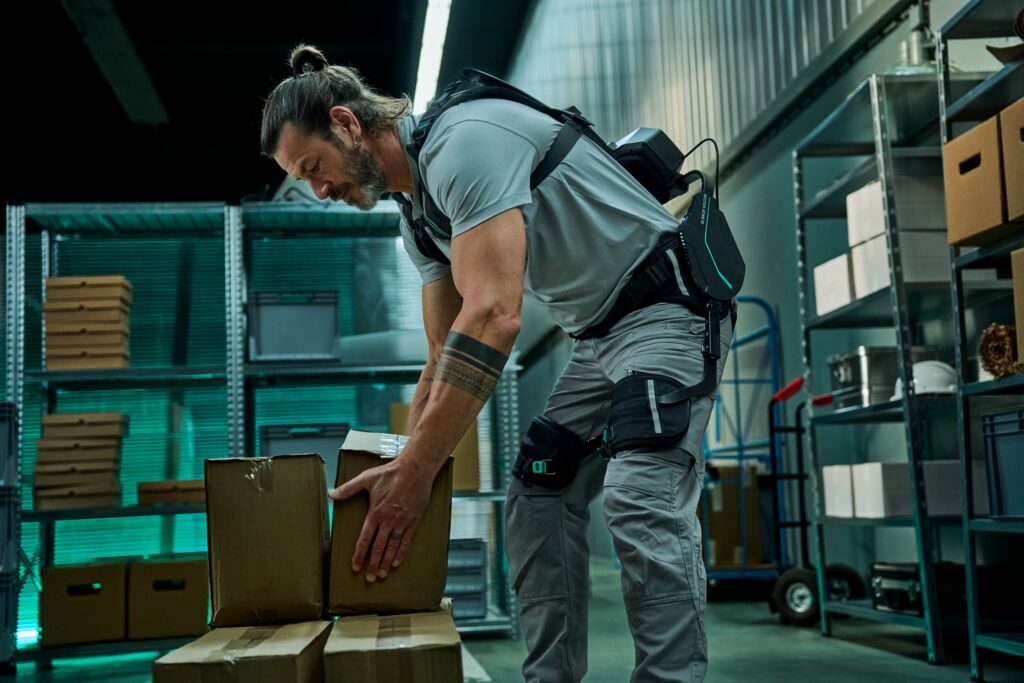 Person hebt Kartons mit Unterst&uuml;tzung eines Exoskeletts.