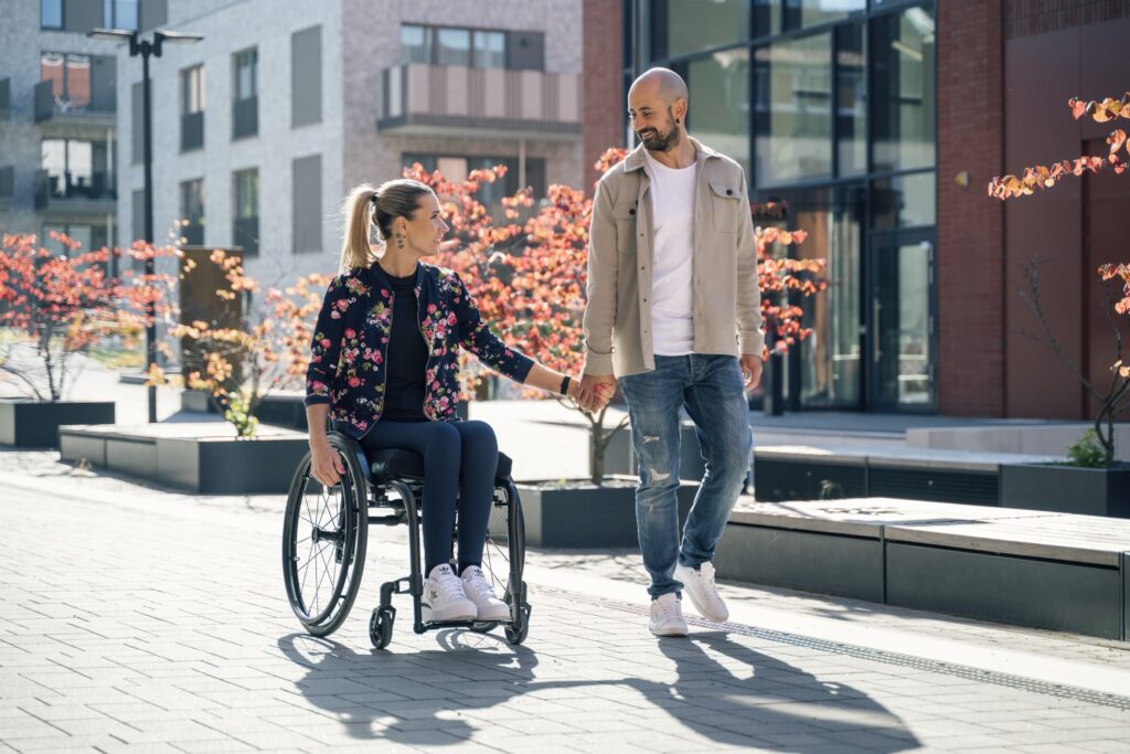 Peggy im Rollstuhl mit Begleitung im Alltag