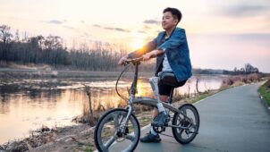 Junger Mensch mit Prothese auf einem Fahrrad am Wasser