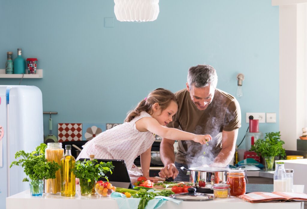 Gemeinsam kochen mit Kindern Kind und Erwachsener kochen gemeinsam in der Küche